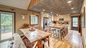 A spacious kitchen with wooden cabinets, a large island with stools, and a deer head mounted on the wall. - Gorgeous Rippling Waters!  Private Hot Tub- Spectacular Views! (Nathrop)
