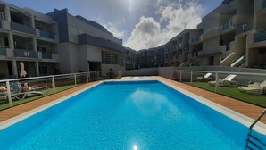 A swimming pool surrounded by modern apartment buildings with balconies.