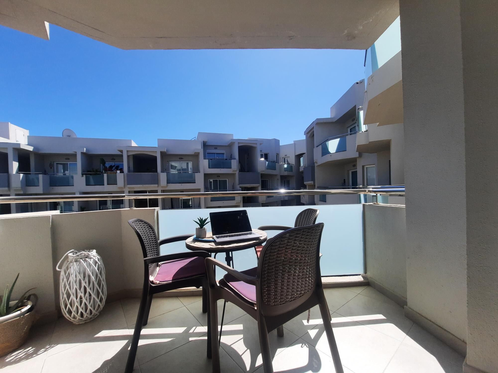 A balcony with a table, two chairs, and a laptop.