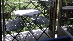 A balcony with a table and chairs, overlooking a building with multiple balconies and greenery. - Sunrise: Elegant 2BR/1BA in the Heart of Central Barcelona, Dreta de l'Eixample (Barcelona)