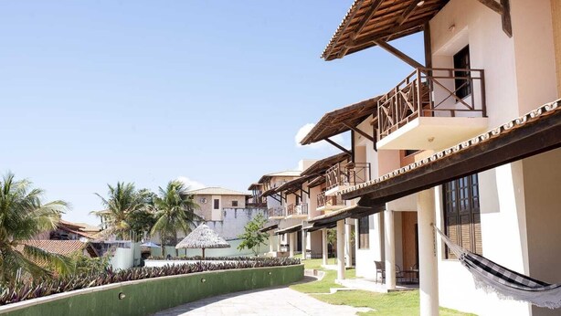 A resort with multiple buildings, outdoor seating areas, and a paved walkway. - Your Beach House 3 min from Beach Park - Cs 01 (CE)