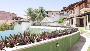 A resort with a pool, thatched-roof structures, and a variety of plants. - Your Beach House 3 min from Beach Park - Cs 01 (CE)
