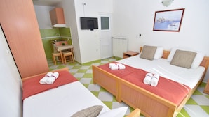 Ett hotellrum med två sängar, ett litet pentry, en TV och en tavla på väggen.