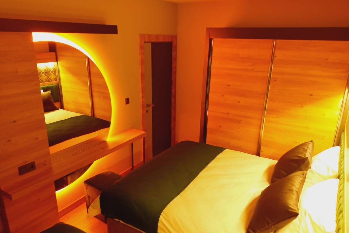 A wooden room with a bed, a bench, and a door.