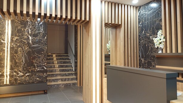 A modern interior with a staircase, wooden slats, and marble walls. - Dinamik Otel (Sarikamis)