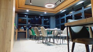 A modern dining area with wooden accents, a central table, and multiple chairs. - Dinamik Otel (Sarikamis)