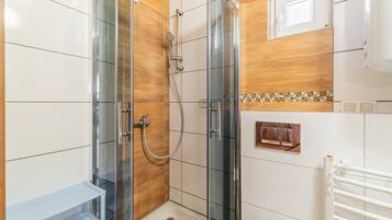 Ein modernes Badezimmer mit einer gläsernen Dusche, weißen Fliesen und einer Wand mit Holzverkleidung.