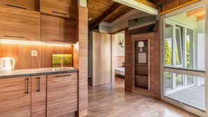 A modern kitchen with wooden cabinetry, a built-in oven, and a large window offering a view of the outdoors. - Holiday homes with pool, close to the beach (Sianozety)