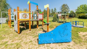 A playground with a wooden climbing structure, a slide, and a blue play area with an anchor design. - Holiday homes with pool, close to the beach (Sianozety)