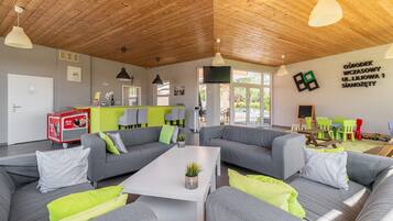 Ein modernes Wohnzimmer mit grauen Sofas, einem weißen Couchtisch und einer Holzbalkendecke.