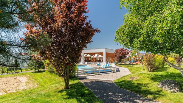 A modern building with a pool area, surrounded by well-maintained grass and trees. - Holiday homes with pool, close to the beach (Sianozety)