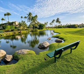 A serene park with a pond, rocks, and a bench.