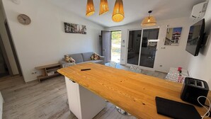 Una cocina moderna con una isla central, iluminación colgante y un comedor con sofá y sillas.