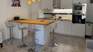 Una cocina moderna con una isla de madera, taburetes de barra de acero inoxidable, armarios blancos, un microondas y un horno.