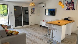 Una cocina moderna con una isla de madera, armarios blancos y un ventanal que da a un balcón.
