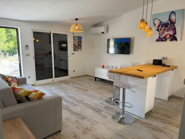 A modern kitchen with a wooden island, white cabinetry, and a glass door leading to a balcony.