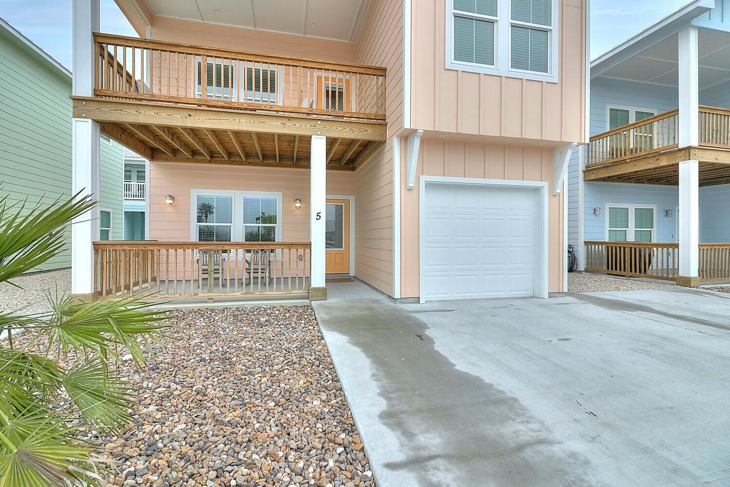 A multi-story residential building with a covered front porch, a garage, and a balcony.