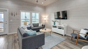 A modern living room with a grey sectional sofa, a round coffee table, and a white entertainment unit.