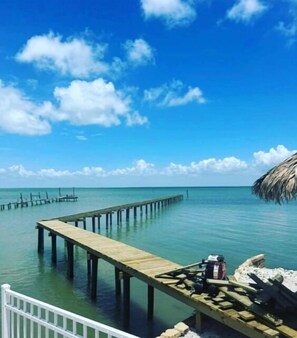 A wooden pier extending into calm turquoise waters under a clear blue sky with scattered clouds. - Copano Breeze 3 Bedroom Home by RedAwning (Rockport)