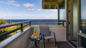 Ein Balkon mit Blick auf das Meer, ein Tisch mit Früchten und ein Stuhl.