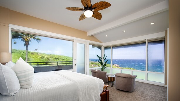 Ein Schlafzimmer mit einem großen Bett, einem Deckenventilator und Meerblick.