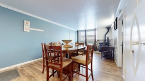 A dining room with a wooden table and chairs, a wall-mounted coat rack, and a stone fireplace. - Krystal Villas East 312 Quaint and Cozy, Great Value for your Mammoth Getaway by RedAwning (Mammoth Lakes)