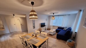 Ett modernt vardagsrum med en matplats, en blå soffa och en tv.