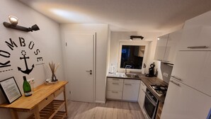 Ett modernt kök med vita skåp, ett träbord och ett fönster med utsikt över staden.