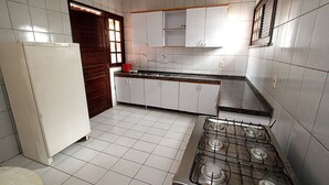 Une cuisine avec des meubles blancs, une cuisinière et un réfrigérateur.
