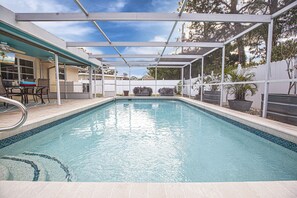 Piscina retangular com borda revestida, cercada por uma vedação branca e coberta por uma estrutura de teto transparente.