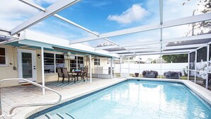 A covered outdoor swimming pool with a patio area, a table, and chairs. - Private heated pool. Shark teeth, close to beaches, downtown, shopping, biking… (Venice)