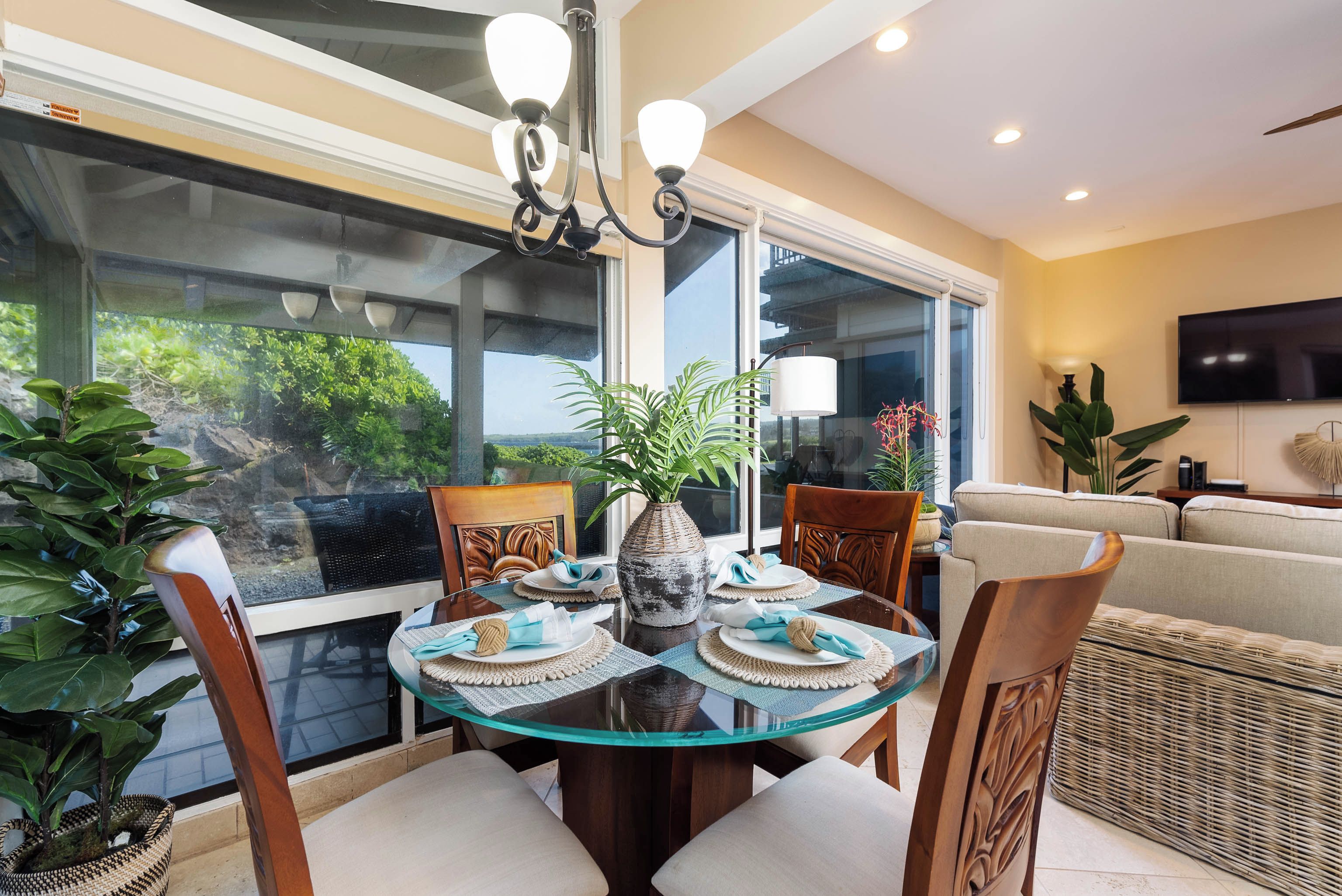 A dining area with a glass table, chairs, and a vase centerpiece.