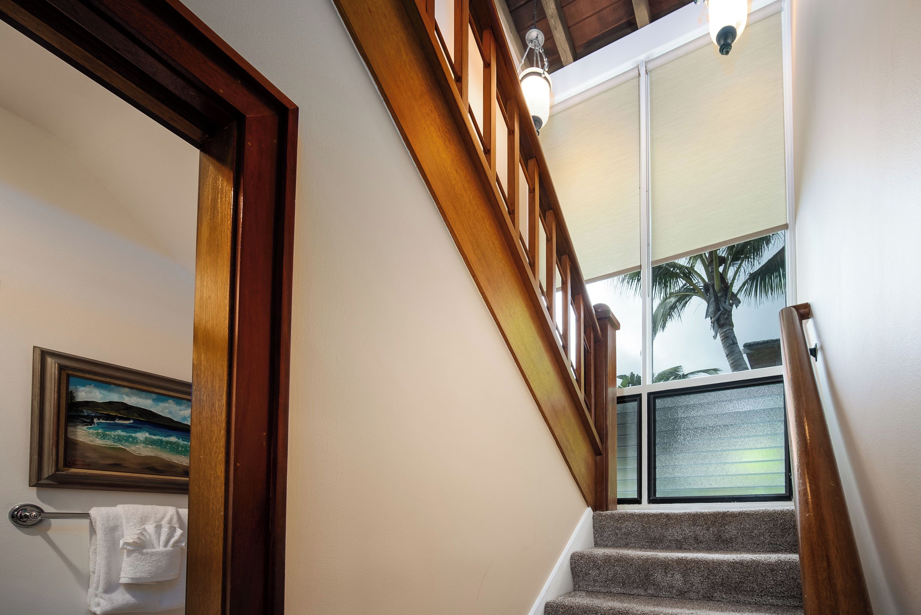 Una escalera con barandillas de madera y vistas a palmeras al exterior.