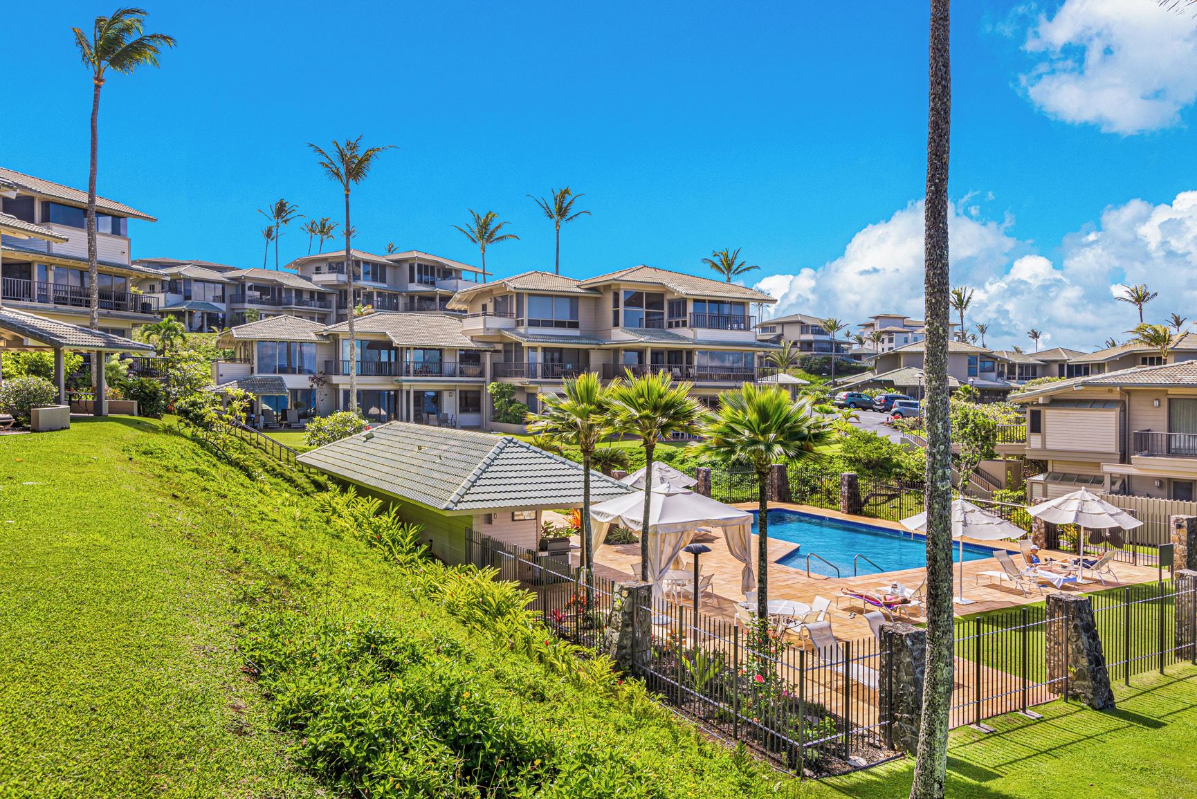 A resort with multiple-story buildings, a swimming pool, and palm trees.