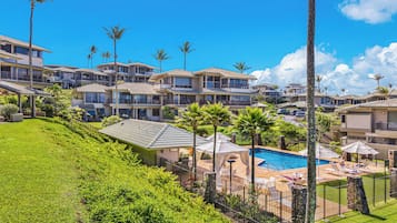 A resort with multiple-story buildings, a swimming pool, and palm trees.