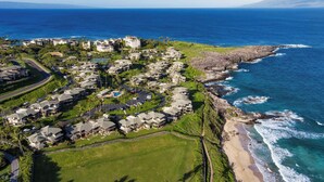 Zona residencial costera con casas a lo largo de la playa, vista despejada del océano y una carretera que serpentea por la propiedad.