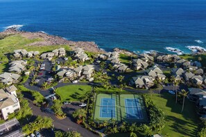 A coastal residential area with houses, a tennis court, and a view of the ocean.
