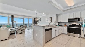 A modern kitchen with a central island, white cabinetry, and stainless steel appliances.
