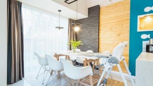 Ein moderner Essbereich mit einem Holztisch, weißen Stühlen und einem Hochstuhl.
