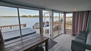 Une pièce dotée d’une grande porte-fenêtre coulissante donnant sur une terrasse avec vue sur un plan d’eau.