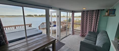 A room with a large sliding glass door leading to a deck overlooking a body of water.