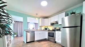 Une cuisine moderne avec des meubles blancs, des appareils en acier inoxydable et un plancher en bois.