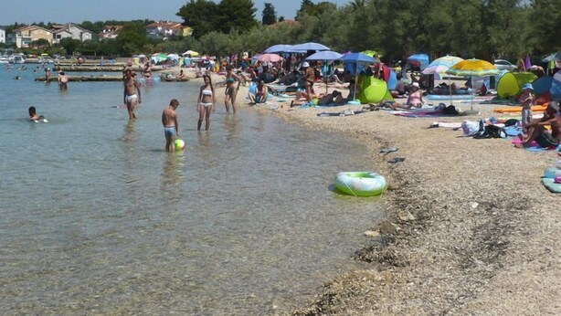 A crowded beach with people swimming and sunbathing, and several colorful umbrellas. - Charming Modern Stay in Biograd (Biograd)