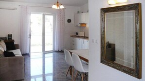 A living room with a sofa, a dining table with chairs, a kitchen area with cabinets and a microwave, and a large mirror on the wall. - Couple Getaway near Adriatic Sea (Biograd)