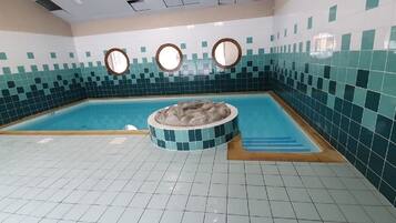Een zwembad met een whirlpool in het midden, omgeven door betegelde muren en een betegelde vloer.