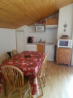 A compact kitchen with a dining table, chairs, a microwave, a toaster, and a dishwasher.