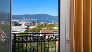 A balcony with a view of a coastal town, buildings, and a mountain in the distance.