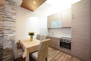 Een moderne keuken met houten kastjes, een inbouwoven en een eethoek met een tafel en stoelen.