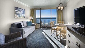 A hotel room with a balcony, a sofa, a dining table, and a TV. - Family Suite at Coral Beach Resort - Full Access to Amenities! (Myrtle Beach)
