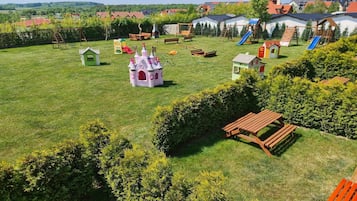 Un amplio espacio al aire libre con césped, juegos infantiles y bancos de madera.
